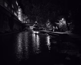 Together in the Darkness Two figures make their way along a quiet path, surrounded by the shadows of the sleeping city. Streetlights illuminate fragments of their surroundings, their...